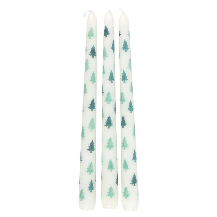 Three white candles with green tree patterns on a white background