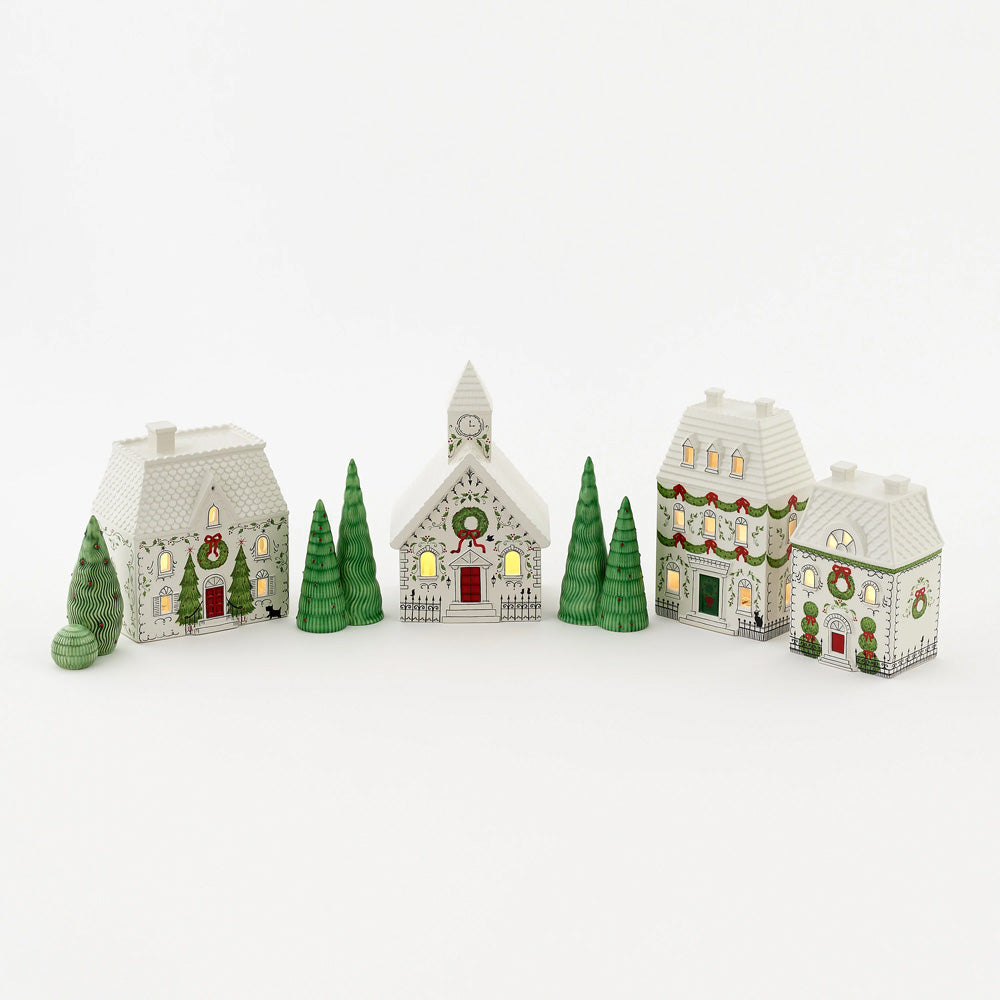 A set of small decorative Christmas village houses and trees in white, green, and red.
