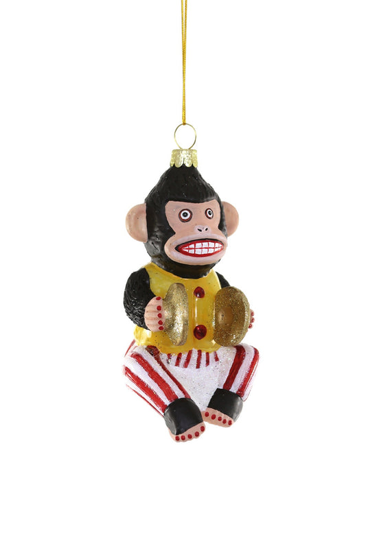 A vintage toy monkey ornament with a yellow shirt, black and red striped pants, and holding gold cymbals, suspended by a gold chain