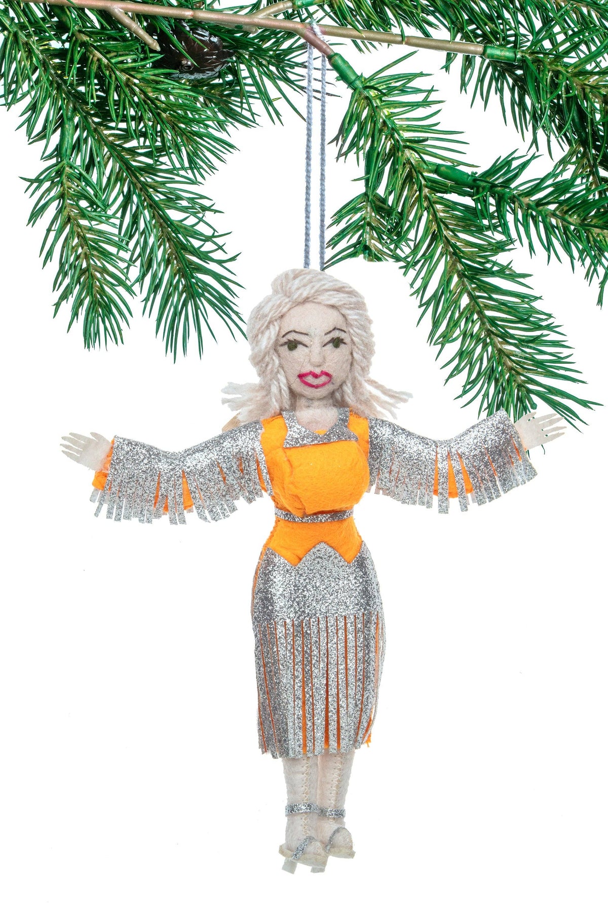 Decorative ornament of Dolly Parton a western theme silver costume with orange accents hanging from a branch.