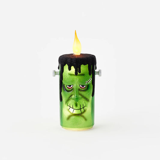 A Frankenstein's monster themed electric candle with a green body, black hair, and a glowing flame.