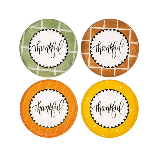 Four round paper plates with 'thankful' text on a plaid patterned background