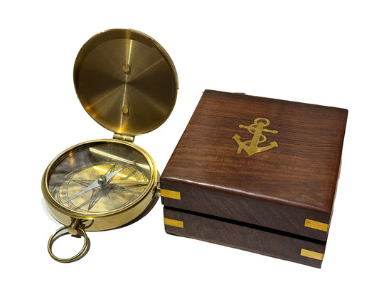 A brass compass includes a dark brown wooden presentation box featuring a gold anchor emblem on the lid.