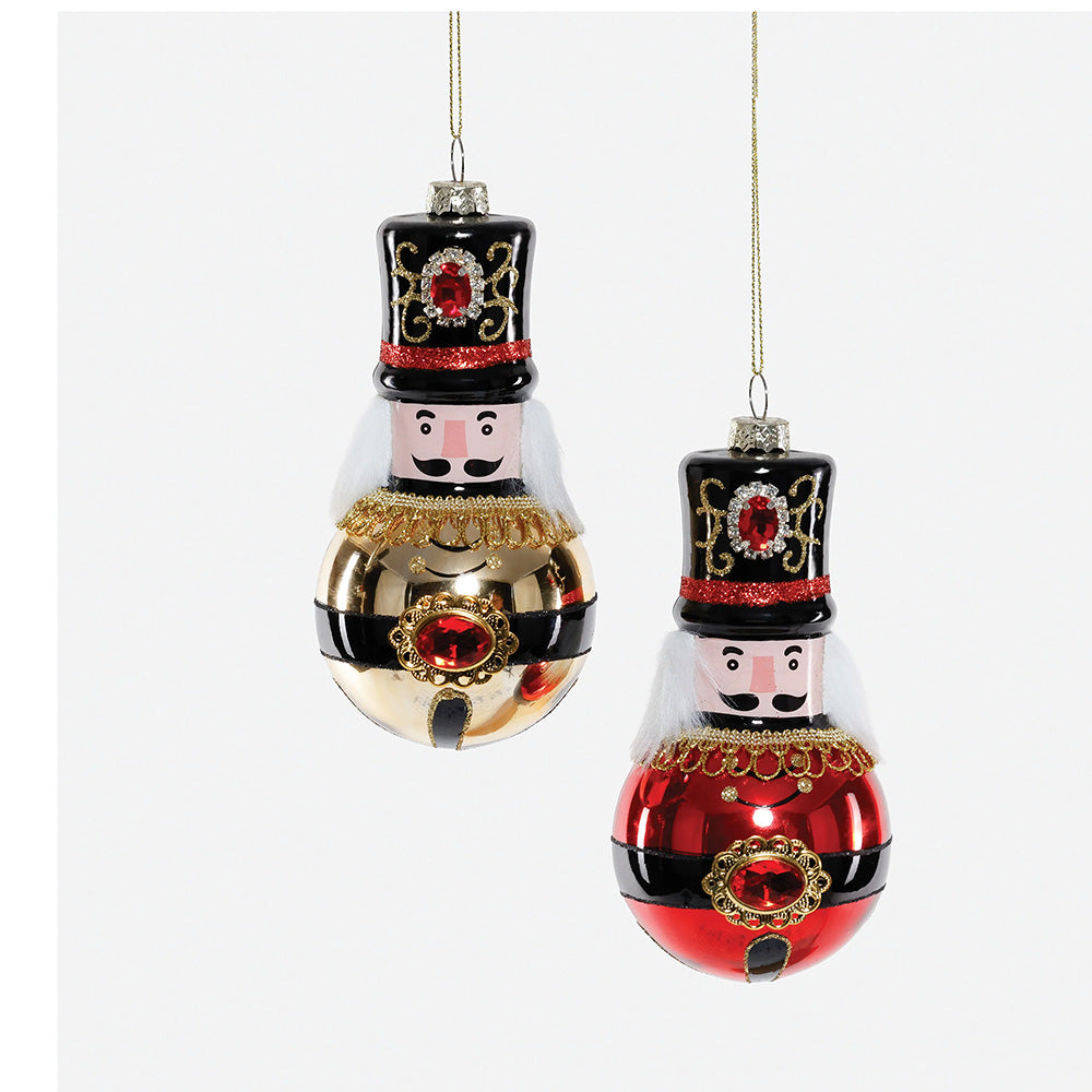 Two hanging Christmas nutcracker ornaments. One ornament is gold and black with a red jewel detail, and the other is red and black with a gold jewel detail.