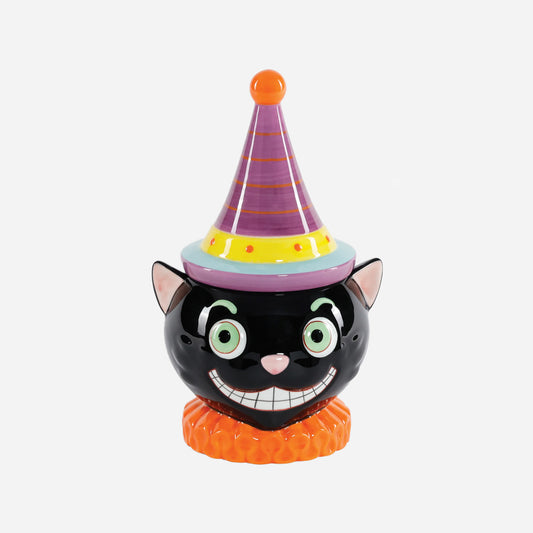 A ceramic black cat figurine cookie jar wearing a purple party hat with orange stripes, a yellow band, and a light blue brim, standing on an orange ruffled base  