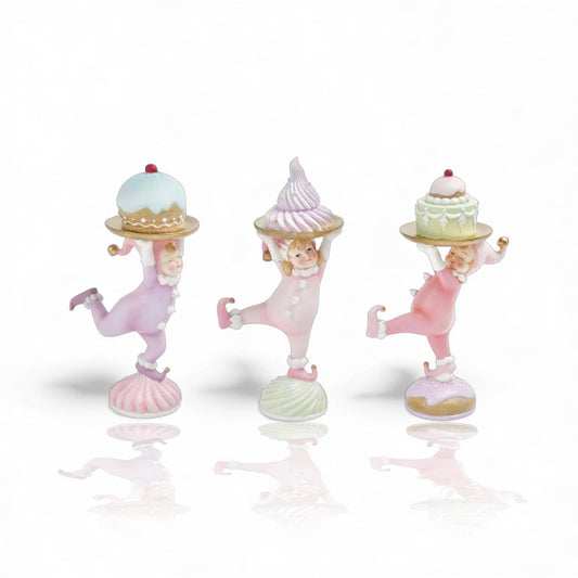 Three child figurines in pastel colors with each holding a tray with a pasty. s 