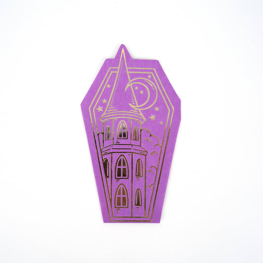 Purple coffin-shaped paper napkins with a gold foil haunted house design  