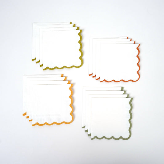 Paper beverage napkins with decorative scalloped edges in colors of red green and orange