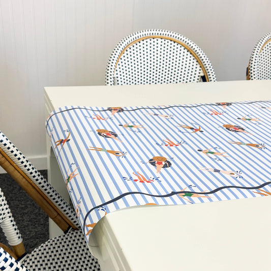 Paper table runner with a blue and white striped featuring swimmers  
