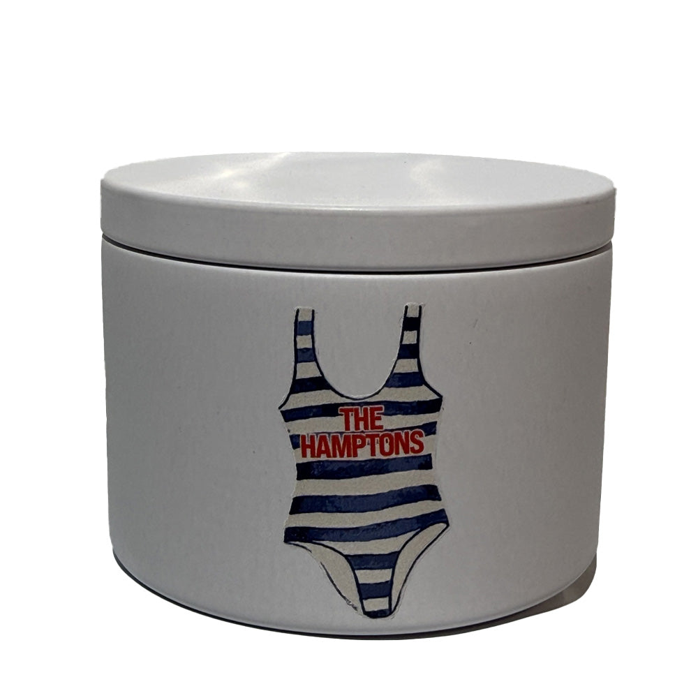 White candle container with a swimsuit graphic and 'The Hamptons' text on a white background