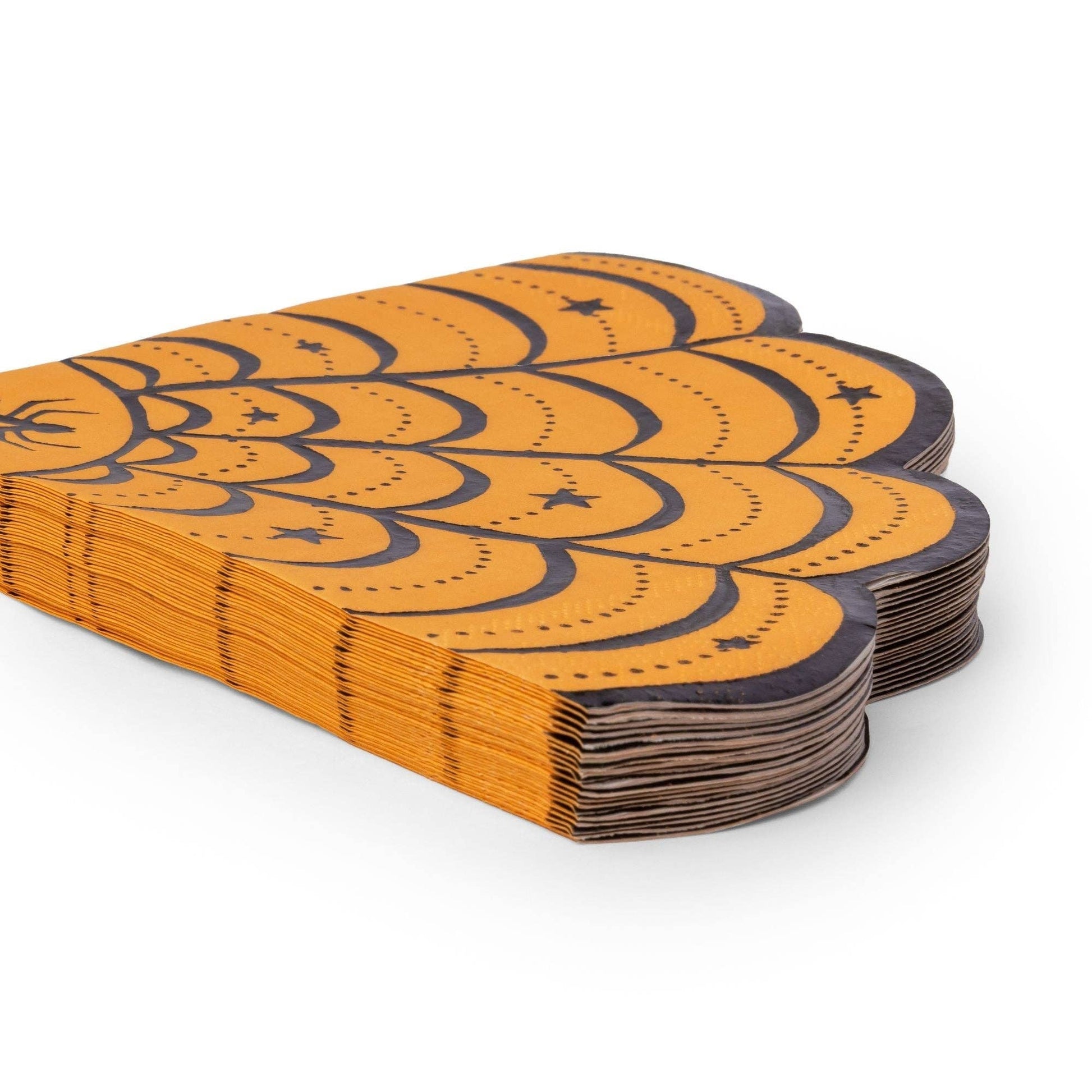A stack of orange and black patterned paper napkins with a scalloped, layered design and small star motifs,