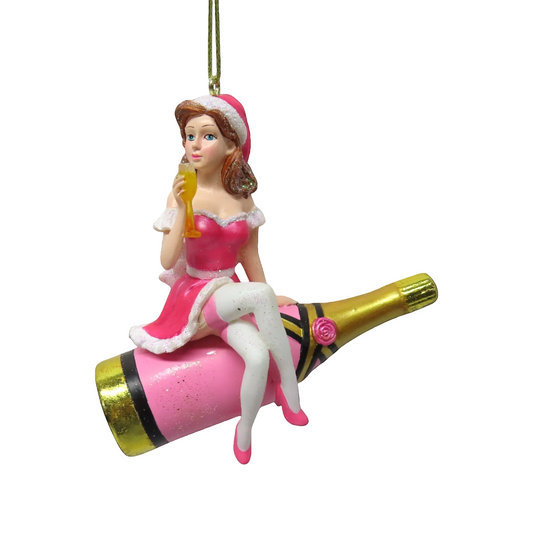 Decorative ornament of a woman in a pink dress sitting on a champagne bottle with a champagne glass.
